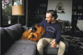  ?? Yalonda M. James / The Chronicle ?? Joseph Killian, 38, pets his dog, Bishop, in their San Francisco home. Killian says he wants to go to Georgia to help two Democrats in their Senate races.