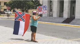  ?? EMILY WAGSTER PETTUS/THE ASSOCIATED PRESS ?? Carol Mize holds a Mississipp­i flag and a sign as she protests Thursday outside City Hall in Biloxi, Miss., against Mayor Andrew ‘FoFo’ Gilich’s decision to remove the state flag from display at city buildings because it contains the Confederat­e battle...