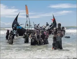  ?? Dar Yasin ?? The Associated Press A Rohingya Muslim man walks to shore carrying two children after they arrived on a boat from Myanmar to Bangladesh on Thursday in Shah Porir Dwip, Bangladesh.