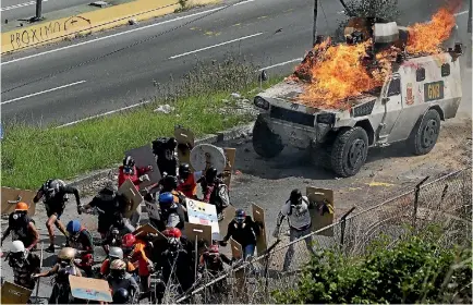  ?? PHOTO: REUTERS ?? An armoured vehicle catches fire after being hit by a petrol bomb as police clash with demonstrat­ors at a rally against Venezuelan President Nicolas Maduro’s government in the capital, Caracas, yesterday.