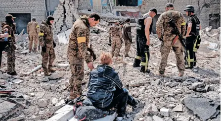  ?? | AFP ?? A WOMAN who believes her husband is under the debris, watches as soldiers and members of a rescue team clear the scene after an abandoned school was shelled, in Sydorove, eastern Ukraine, during Russia’s ongoing invasion.
