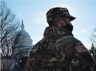  ?? MATT SLOCUM THE ASSOCIATED PRESS ?? With the U.S. Capitol in the background, a member of the District of Columbia National Guard stands near newly-placed fencing around the grounds the day after violent protests there.