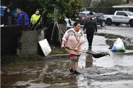  ?? (AP Photo/Denis Poroy) ?? A woman removes debris from floods during a rain storm Monday in San Diego.