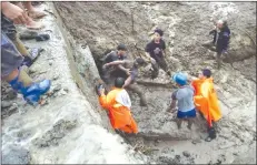  ?? (Natonin PNP via Dave Leprozo) ?? A survivor on Thursday, November 1, is led out by rescuers from the collapsed DPWH building which was buried by a landslide at the height of Typhoon "Rosita" on October 30. Around 13 other people are still believed to be trapped in the debris and mud.