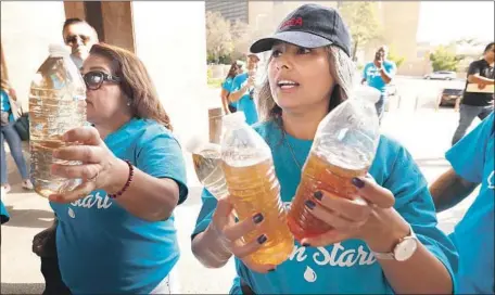  ?? Al Seib Los Angeles Times ?? LUCIA CAMACHO and other residents display bottles of brown water from Compton taps before Wednesday’s vote on the water district.