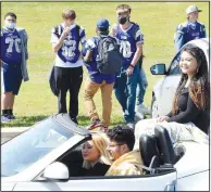  ??  ?? Junior maid Lilly Lee (right) passes members of the Bulldog football team during a modified homecoming parade in the parking lot at Decatur High School.
(NWA Democrat-Gazette/Mike Eckels)