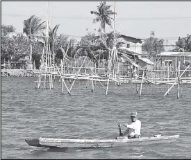  ?? CESAR RAMIREZ ?? A boatman paddles past near a fishing device locally called ‘batikwas’ in a river in Dagupan City.