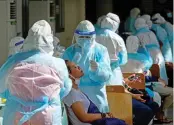  ??  ?? People (left) wait in a queue to get their samples taken, as medical workers (right) take swab samples from others during a mass testing event at a sport complex, in Thailand’s capital city of Bangkok on Saturday