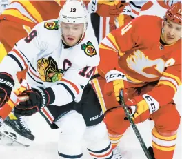  ?? JEFF MCINTOSH/AP ?? Jonathan Toews, left, and Calgary Flames forward Mikael Backlund chase the puck during the first period of Tuesday night’s game.