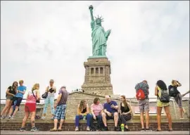  ?? DREW ANGERER Getty Images ?? PEOPLE visit the Statue of Liberty. A Trump administra­tion official gave his interpreta­tion of Emma Lazarus’ famous poem on the pedestal of the statue.