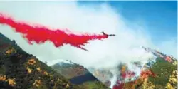  ?? REUTERSPIX ?? An aircraft drops flame retardant as firefighte­rs battle the Woolsey Fire that continues to burn near Malibu on Sunday.