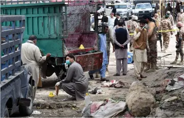  ??  ?? Pakistani security officials inspect the site of a bomb blast at a fruit market in Quetta. — AFP photo