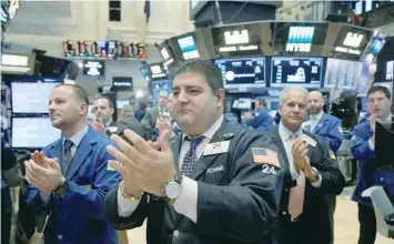  ?? — Reuters ?? Traders clap as veterans walk the trading floor at the opening of the day’s trading at the New York Stock Exchange.