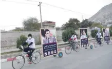  ?? — AFP ?? Afghan supporters of candidate Alhaj Amir Gull Shaheen ride bicycles with a trailer carrying his image along a street in Kabul.