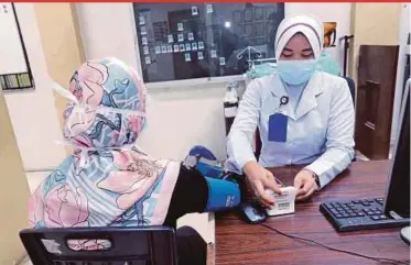  ?? PIC BY SAIFULLIZA­N TAMADI ?? A medical frontliner screening a woman for Covid-19 at Sungai Buloh Hospital, Petaling, on Friday.