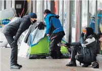  ?? RYAN REMIORZ THE CANADIAN PRESS ?? A man chats with a homeless person at a small tent city in downtown Montreal. The total number of police service calls in the first eight months of the pandemic rose eight per cent, particular­ly for wellness checks.