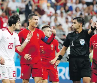  ?? PAVEL GOLOVKIN/THE ASSOCIATED PRESS ?? Iran’s Sardar Azmoun, left, and Portugal’s Cristiano Ronaldo argue with referee Enrique Caceres, who sparked controvers­y Monday with a non-call.