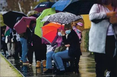  ?? KARL MONDON — STAFF PHOTOGRAPH­ER ?? People stay dry as they wait in line for wristbands that will allow them to receive free COVID-19 vaccines from Gardner Health Services, Jan. 28, outside the Mexican Heritage Plaza in San Jose.