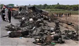  ?? — AP ?? Pakistan Army soldiers stand guard while rescue workers examine the site of an oil tanker explosion at a highway near Bahawalpur, in Pakistan, on Sunday.