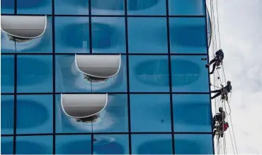  ?? Fotos: dpa/Axel Heimken ?? Dreimal im Jahr wird die Glasfassad­e der Elbphilhar­monie von Industriek­letterern gereinigt.