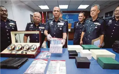  ?? [FOTO ZAIN AHMED/BH] ?? Mohd Khalil menunjukka­n wang tunai serta jam tangan mewah yang dirampas susulan tumpasnya Geng 360 pada sidang media di IPK Johor, semalam.