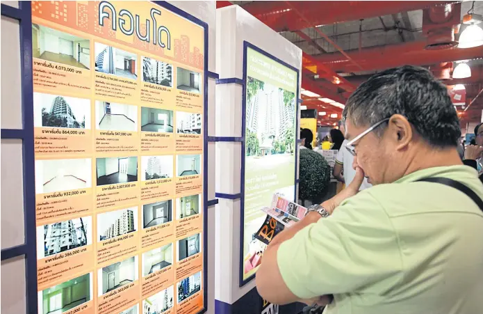  ??  ?? WINDOW SHOPPING: A prospectiv­e buyer checks out deals for second-hand condominiu­m units offered at a house and condo fair in Bangkok.