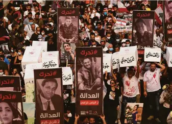  ?? Hassan Ammar / Associated Press ?? Relatives of victims of the deadly 2020 Beirut port explosion hold portraits of loved ones and symbolic coffins to mark the second anniversar­y of the blast, outside the Lebanon port.