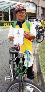  ??  ?? I did it: Salleh posing with his old bicycle and certificat­e after finishing the 10km ride in Kuching.