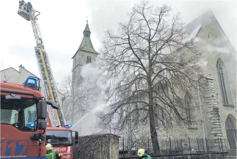  ?? ARCHIVFOTO: JASMIN BÜHLER ?? Rauch steigt aus dem Dach der Kirche St. Jodok auf. Das Dach eines Seitenschi­ffs wurde bei dem Brand im März zerstört.