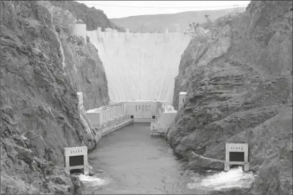  ?? LENNOX MCLENDON/AP ?? WATER STARTS TO FLOW FROM THE LOWER JET FLOW GATES at Hoover Dam near Boulder City, Nev., on June 11, 1998, during testing of the newly installed devices. Americans wondering whether a nearby dam could be dangerous can look up the condition and hazard ratings of tens of thousands of dams nationwide using an online database run by the federal government. But they won’t find the condition of Hoover Dam, which impounds one the nation’s largest reservoirs on the border of Nevada and Arizona.