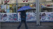  ?? DAMIAN DOVARGANES—ASSOCIATED PRESS ?? A pedestrian walks past a 99-Cents store under light rain in Los Angeles Wednesday, Dec. 5, 2018. A fall storm is causing slick conditions on Southern California freeways but isn’t expected to generate enough rain to trigger mudslides or debris flows on hillsides charred by recent fires.