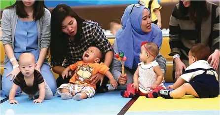  ?? GUSLAN GUMILANG / JAWA POS ?? LHO, KOK NANGIS: Bayi Dirgantara (dua dari kiri) sedang dibujuk ibunya agar mau merangkak. Sementara itu, bayi Sam Raharjo (kiri) sudah siap merangkak.