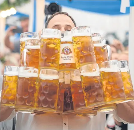  ??  ?? Oliver Struempfel competes during his world record attempt, carrying 27 beer mugs during the traditiona­l Gillamoos festival at Abensberg, in Germany. He succeeded.