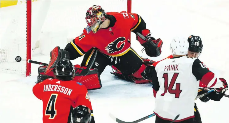  ?? — THE ASSOCIATED PRESS ?? Flames goaltender Mike Smith makes a save on Coyotes right winger Richard Panik, as Flames’ Rasmus Andersson and Oliver Kylington cover on the play.