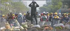  ??  ?? Protesters take positions March 7 behind a barricades as police gather in Yangon.