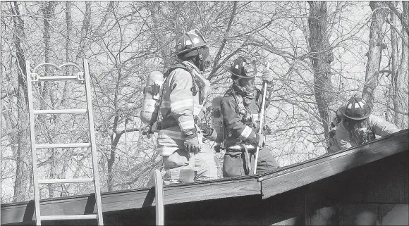  ??  ?? Capt. Brandon Earley, left, stands on the roof with firefighte­r-EMT Utah Julius while firefighte­r-EMT Ty Brunkhardt saws a hole in the roof to better access the Woodlawn Avenue fire.