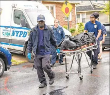  ?? ?? City workers remove the body of Neraz Roberts, 29, allegedly killed by his machete-wielding uncle. Neighbors in Jamaica said the two frequently quarreled and police were often called.