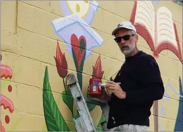  ?? MICHELLE N. LYNCH— MEDIANEWS GROUP ?? Mike Miller of West Reading, a Wyomissing School District art teacher, puts the finishing touches on a mural Sunday, April 25. The mural is the first of several planned for Sander Alley in Kutztown.