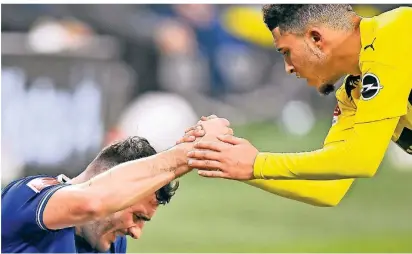  ?? FOTO: MARTIN MEISSNER/AP ?? Mitleid vom siegreiche­n Gegner: Dortmunds Jadon Sancho (r.) hilft Schalkes Sead Kolasinac auf.