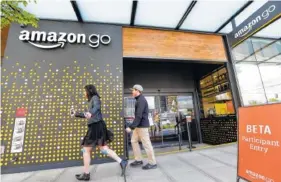  ?? ASSOCIATED PRESS FILE PHOTO ?? People walk past an Amazon Go store, open only to Amazon employees, in Seattle. Amazon Go shops are convenienc­e stores that don’t use cashiers or checkout lines, but use a tracking system of sensors, algorithms and cameras to determine what a customer...