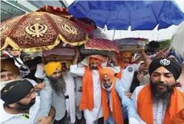  ?? — PTI ?? Members of the Sikh community ceremonial­ly receive the Guru Granth Sahib as it was brought to India from Afghanista­n at IGI Airport’s Terminal 3 in New Delhi on Tuesday.