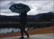  ?? ARIC CRABB — STAFF PHOTOGRAPH­ER ?? A pedestrian walks around Lake Elizabeth with an umbrella on Sunday in Fremont. Heavier rains are expected.