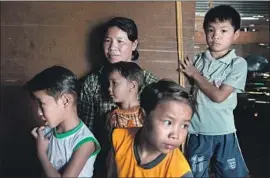  ??  ?? MYINT SEIN and her children in Inn Wine Pahel. Her husband, Htay Aung, a farmer who tried to help others get back confiscate­d land, was beaten to death.