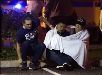  ?? MARK J. TERRILL — THE ASSOCIATED PRESS ?? People comfort each other as they sit near the scene Thursday in Thousand Oaks where a gunman opened fire Wednesday inside a country dance bar crowded with hundreds of people on “college night.”