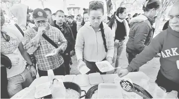  ??  ?? Cuban migrants, who were stranded on their way to the US, receive food from civil society at Juarez square in Nuevo Laredo, Mexico. — Reuters photo