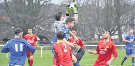  ??  ?? Glantraeth’s Andy Barker (blue) challenges for the ball against Llanrwst