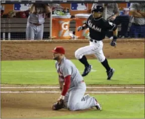  ?? LYNNE SLADKY — THE ASSOCIATED PRESS ?? Miami’s Ichiro Suzuki, rear, runs past St. Louis first baseman Matt Adams after hitting a double during the seventh inning Thursday in Miami. The hit left Ichiro just two short of 3,000.