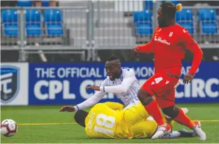  ??  ?? Forge FC goalkeeper Quillan Roberts, bottom left, makes a save on FC Edmonton forward Oumar Diouck, top left, while Forge defender Dominic Samuel looks on. Easton Ongaro scored late for Edmonton to earn his club a point.