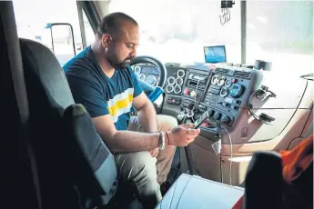  ?? DAVID PAUL MORRIS BLOOMBERG FILE PHOTO ?? Amit Sekhri checks his smartphone for possible jobs and bids using the Convoy applicatio­n in his truck in Patterson, Calif.