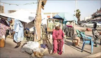  ?? AFP ?? A man sits on a chair by the street as he looks at people going about with their daily life in the commercial centre, of the capital Nouakchott.